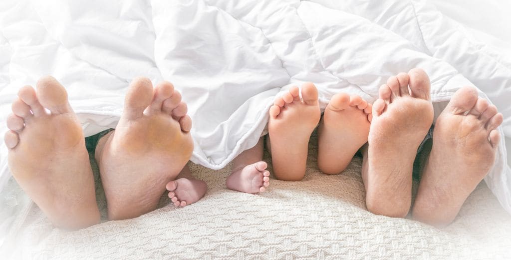 pies de dos padres y dos hijos en la cama