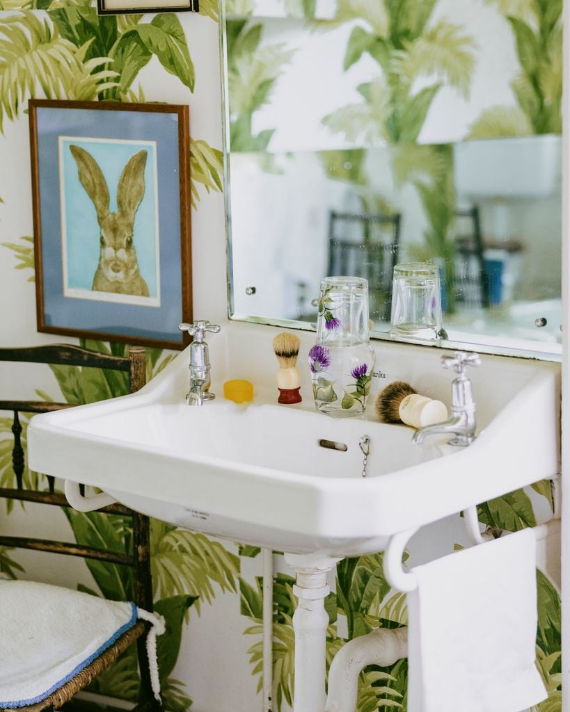 Baño con papel pintado tropical y lavabo retro