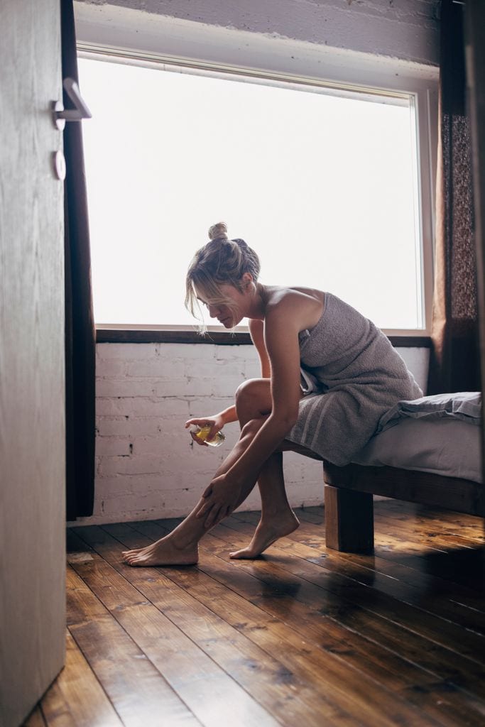 Una mujer aplicándose aceite corporal después de la ducha