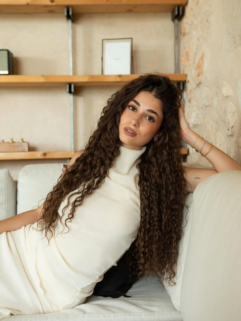 Alejandra Díaz con pelo rizado largo y definido en tono castaño oscuro