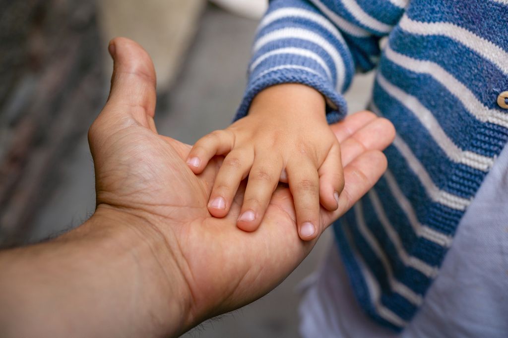 Padre sosteniendo la mano de su hijo pequeño