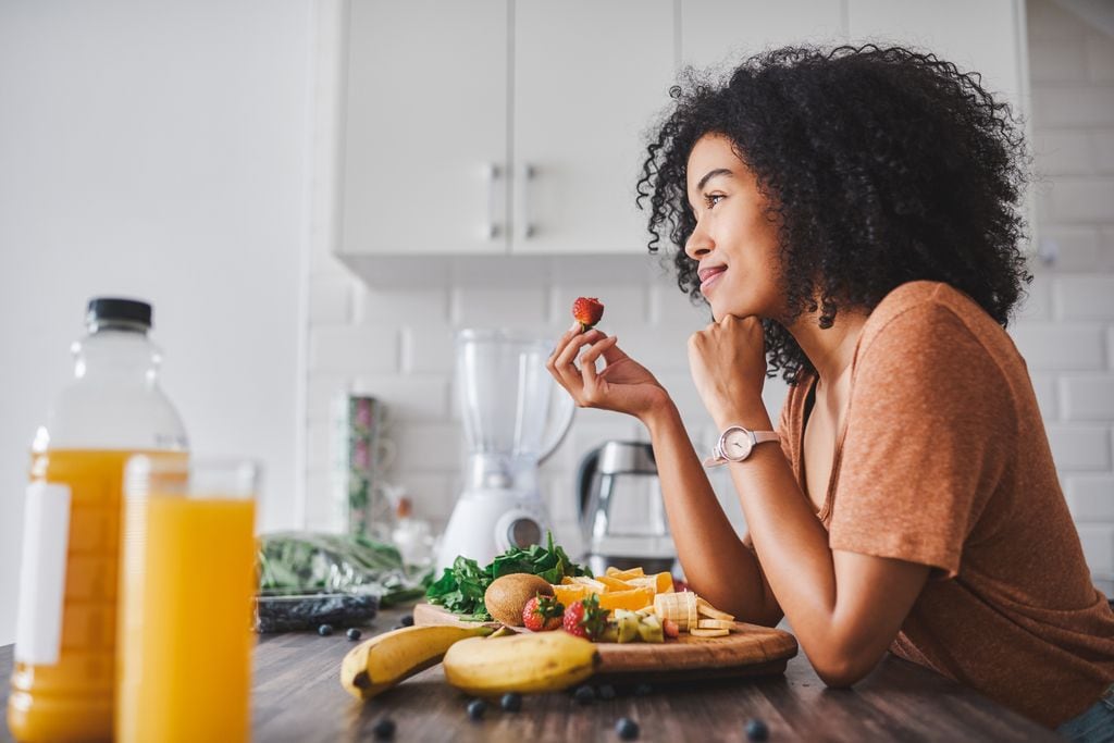 mujer comiendo fruta en la cocina