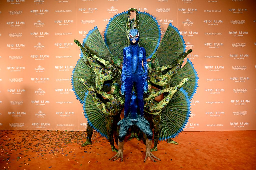 Heidi Klum disfrazada como pavo real con ayuda de algunos acróbatas del Cirque du Soleil