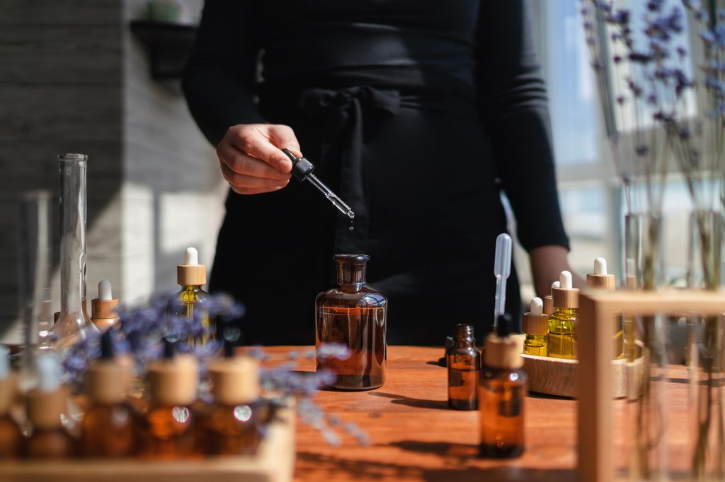 Mujer preparando un líquido aromático para difusor o perfume a partir de aceite esencial de flores.