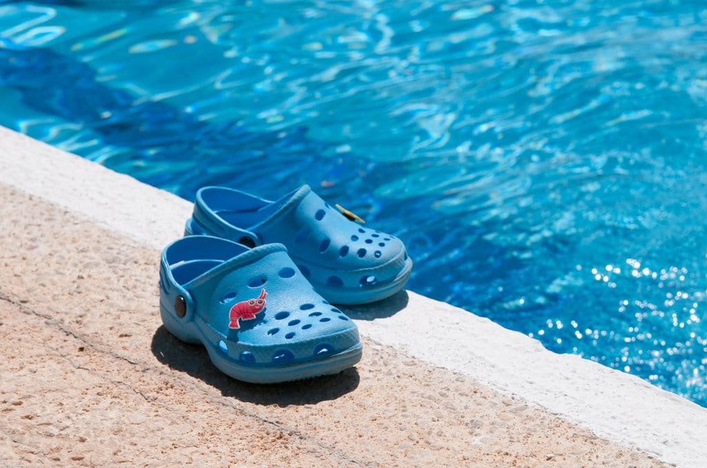 Zapatillas tipo crocs al borde de la piscina