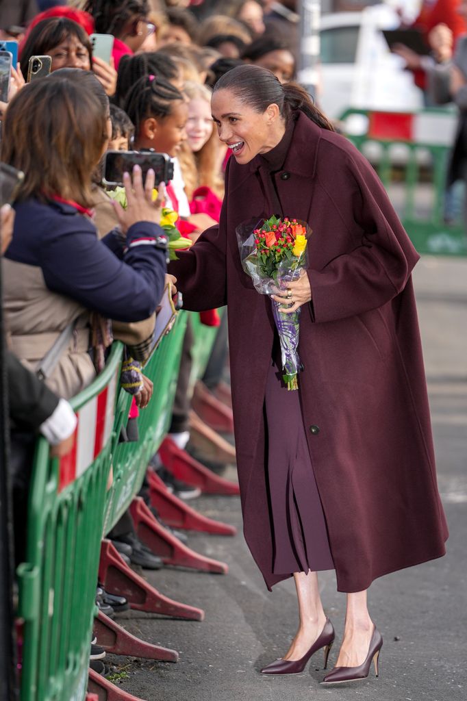 Meghan lució impecable con un elegante atuendo en tinos burdeos.