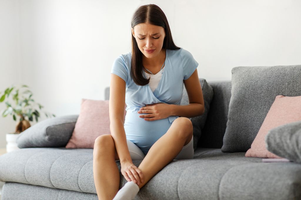 Embarazada con gesto de dolor por varices en las piernas