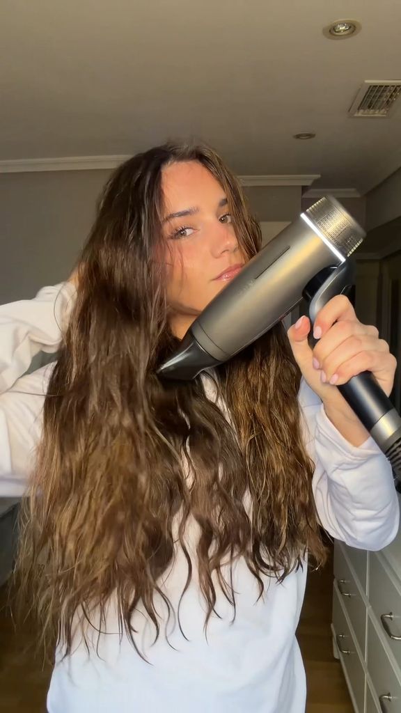 mujer usando secador en cabello ondulado para eliminar residuos de champú en seco