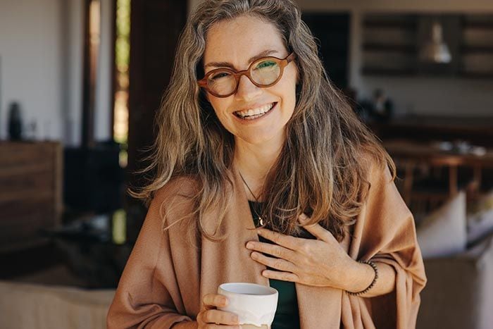 mujer madura alegre tomando un café