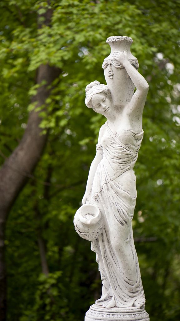 Escultura de estilo clásico en un verde jardín rodeado de frondosa vegetación