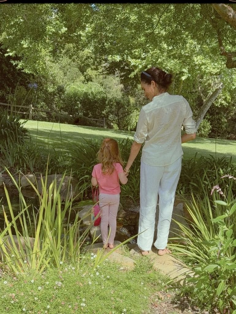 Meghan descalza con su hija Lilibet en el jardín de su casa.