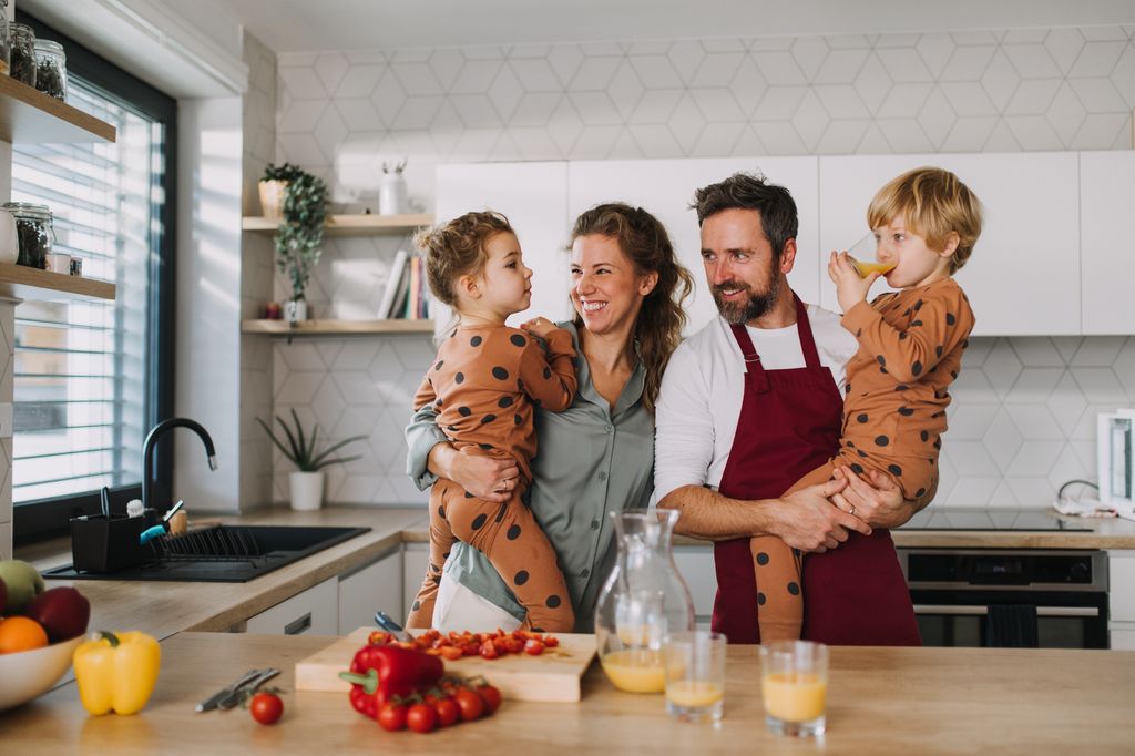 padre y madre con sus hijos en la cocina, preparando el desayuno juntos