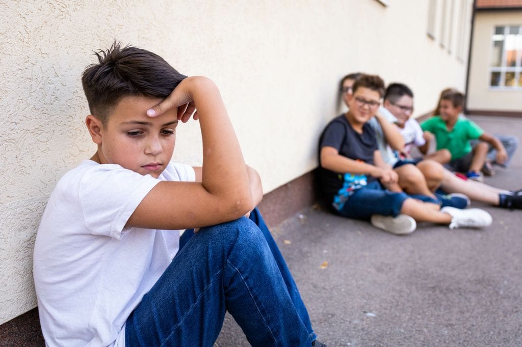 Niño triste en el recreo porque sus compañeros se burlan de él