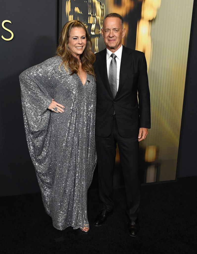 Plano entero de Rita Wilson y Tom Hanks con vestido de lentejuelas y traje negro