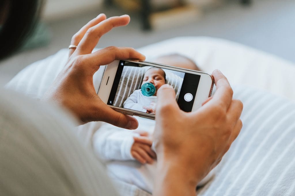Mujer tomando foto a un recién nacido con chupete