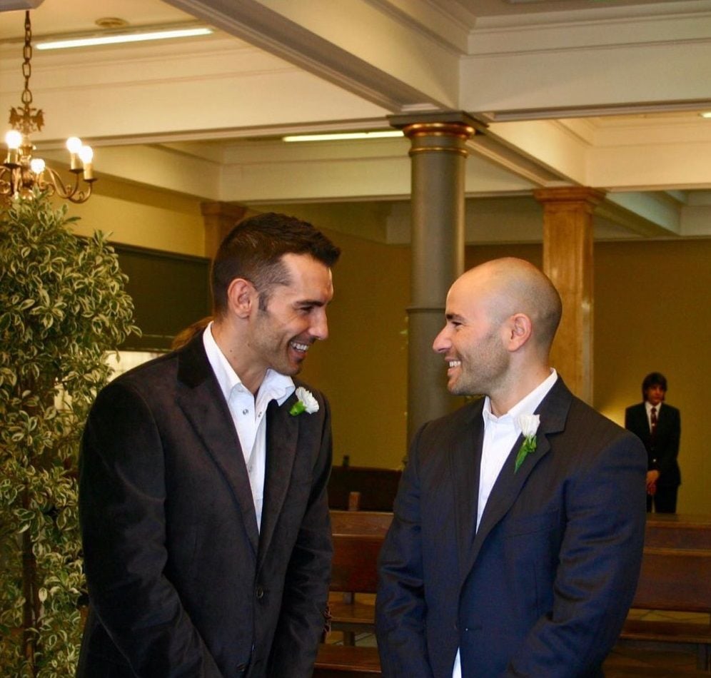 Plano medio de Jesús Vázquez con su marido Roberto Cortés vestidos de traje