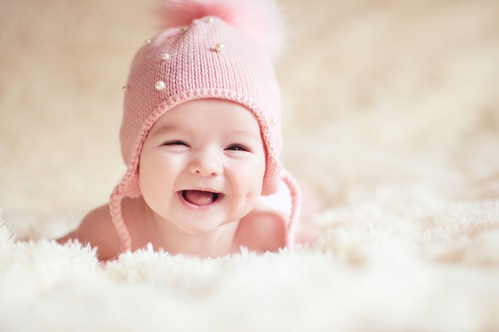 Bebé niña, con un gorrito de lana rosa, sonríe