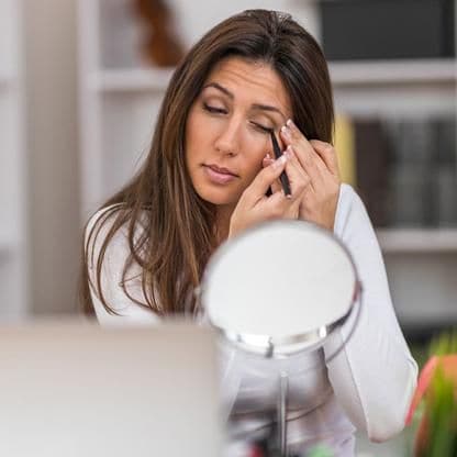 mujer aplica delineador de ojos frente a un espejo peque o