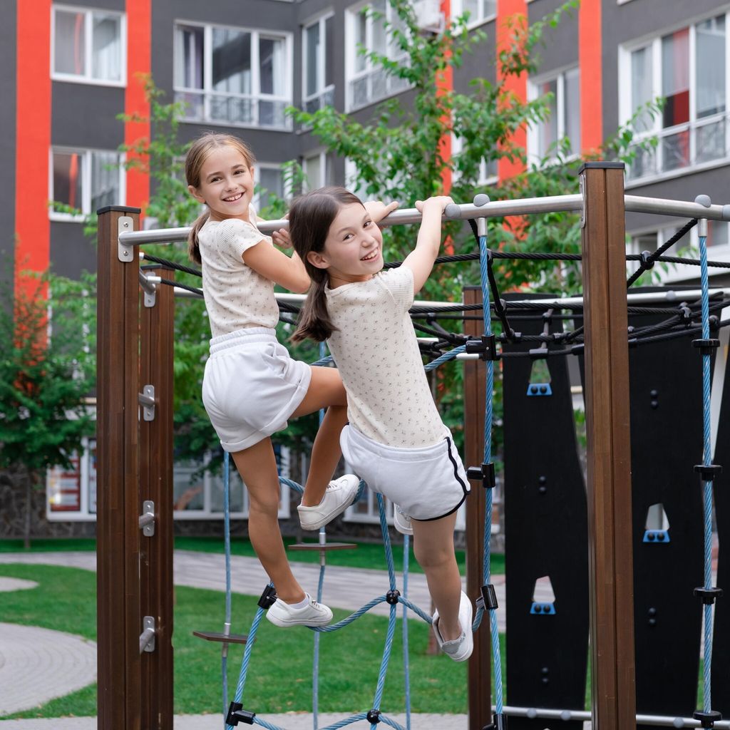 two pretty teen girls playing on a modern playground in identical clothes. sister, bffs. sisterhood, friendship.