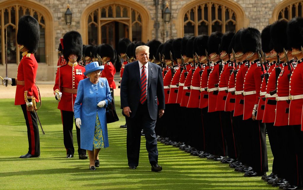 Plano entero de Donald Trump con Isabel II en una visita con los guardias reales