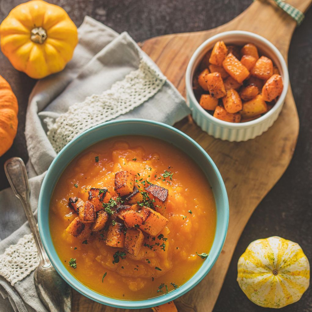 Homemade pumpkin cream soup with baked pumpkin pieces in a blue bowl