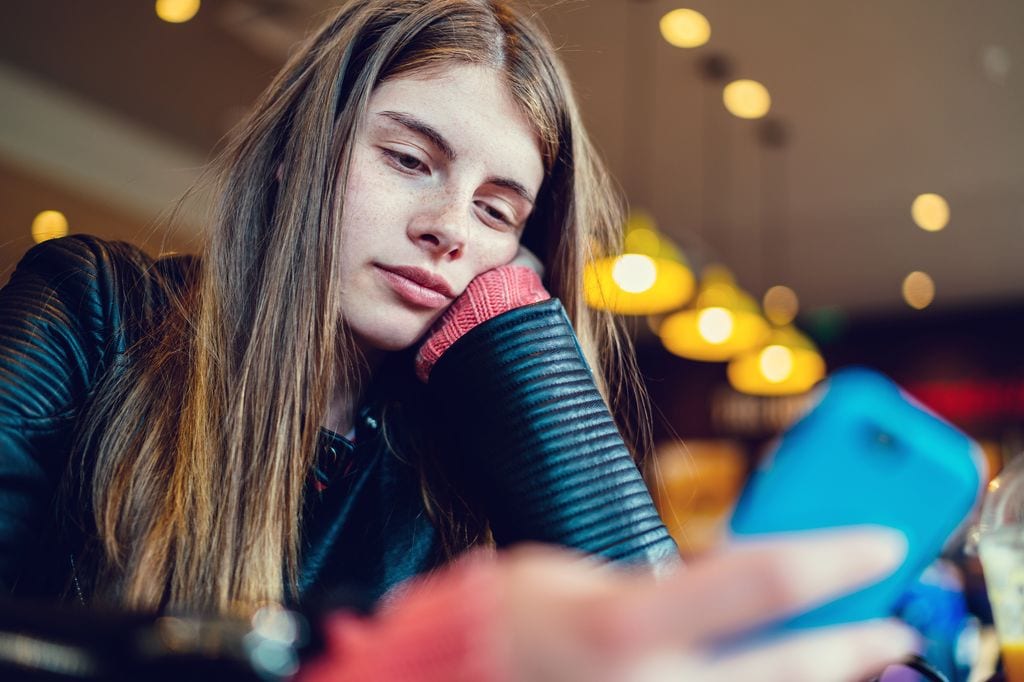 Adolescente seria mira el móvil