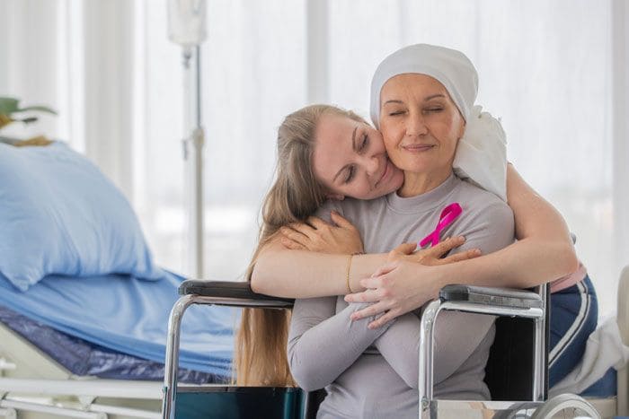 mujer con cáncer abrazada por una chica