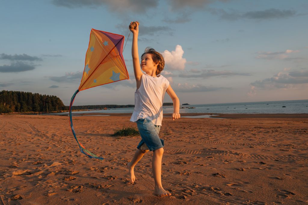niño jugando con una cometa en la playa