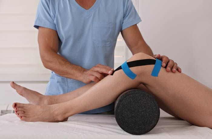 mujer con dolor en la rodilla en el fisioterapeuta