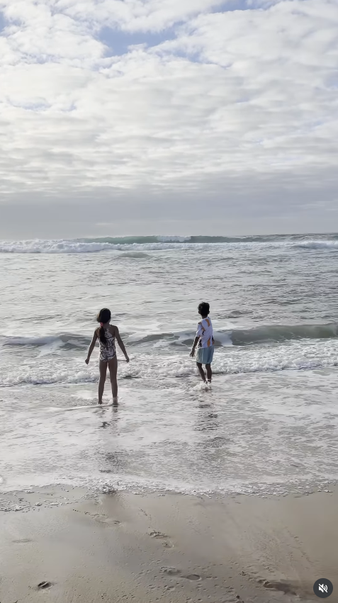 Los mellizos Eva María y Mateo disfrutan de un divertido momento junto al mar, jugando con las olas y aprovechando un día de playa