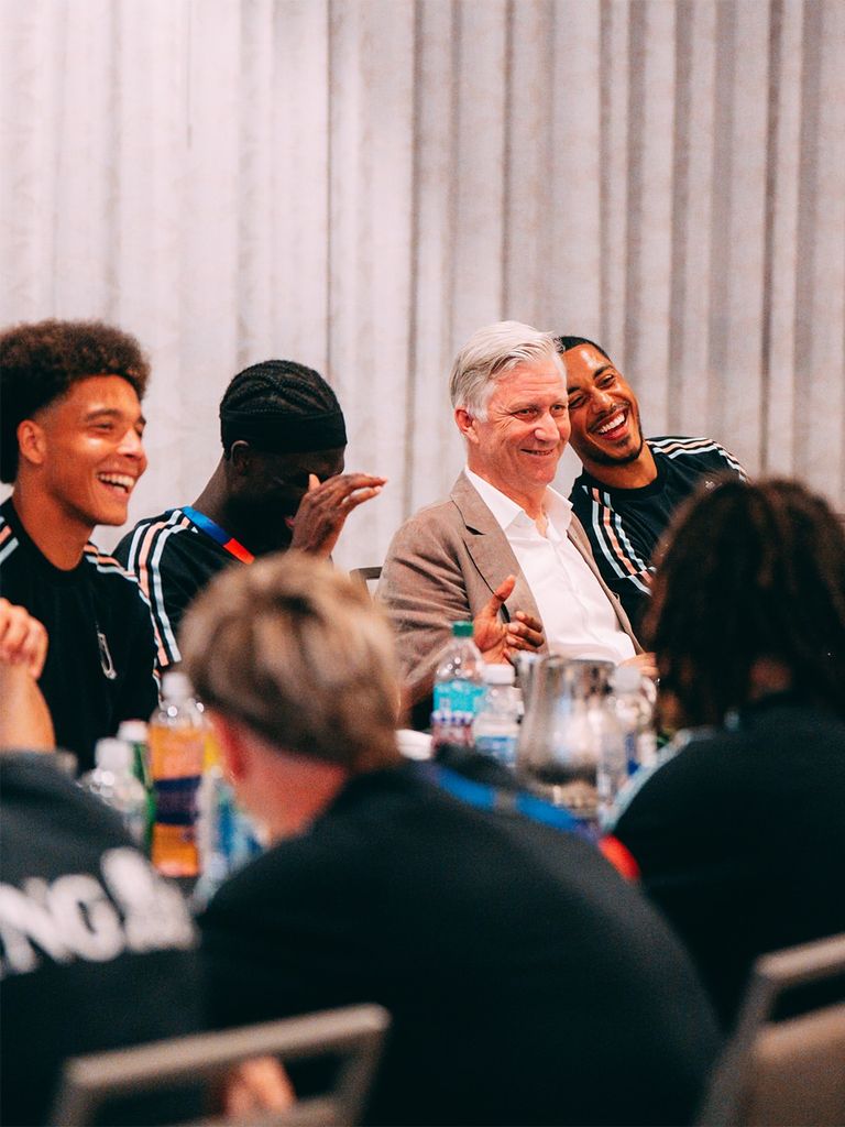 El rey de los belgas rie con los jugadores de la selección de su país durante la cena