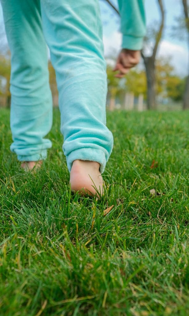 Niño caminando descalzo sobre el césped