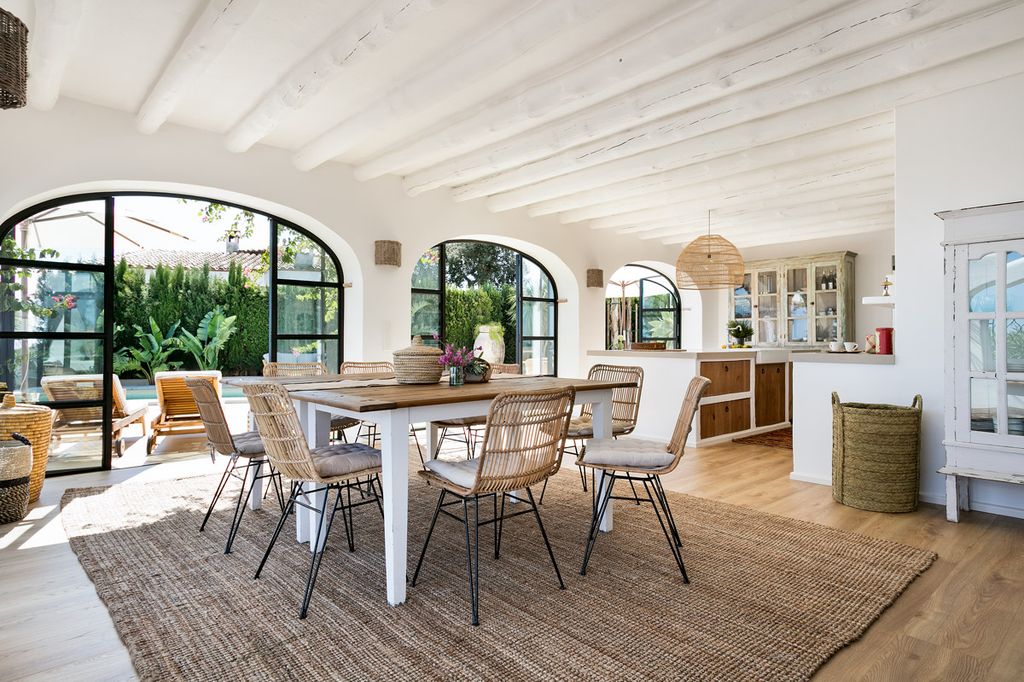 Comedor abierto a la cocina y todo el interior con conexión visual al verde jardín con piscina