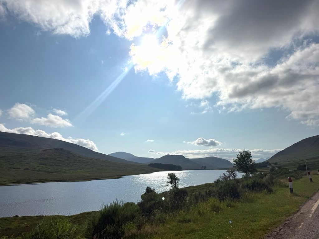 Meghan mostró una hermosa vista de un lago rodeado por colinas verdes.