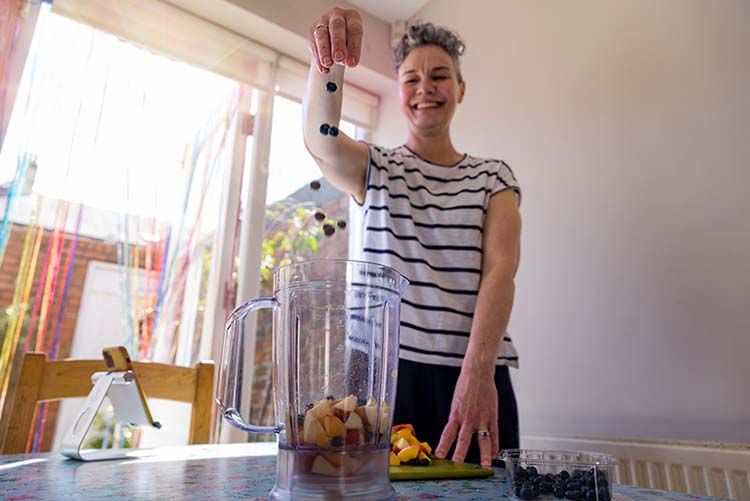 Mujer haciéndose un batido con arándanos, que contienen potentes antioxidantes
