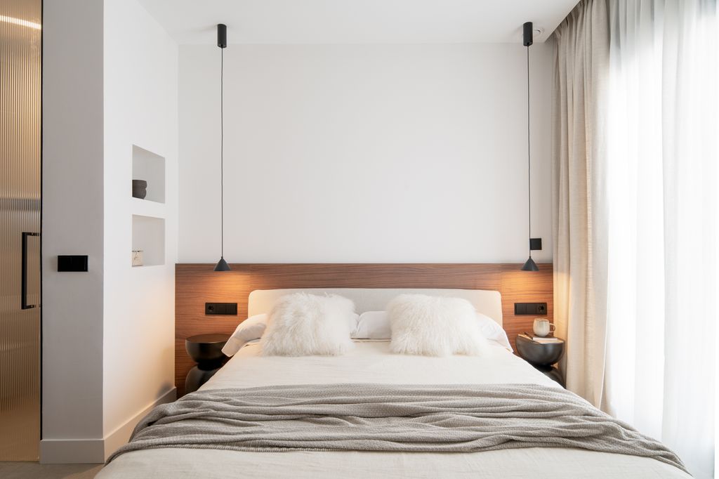 Dormitorio con cabecero de madera y mesillas negras