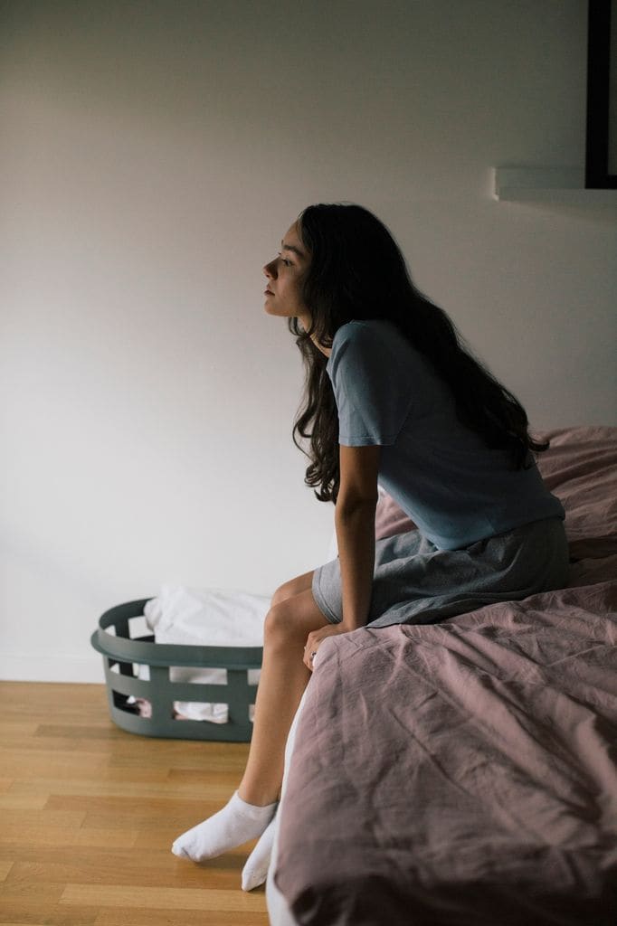 chica pensando sentada cama