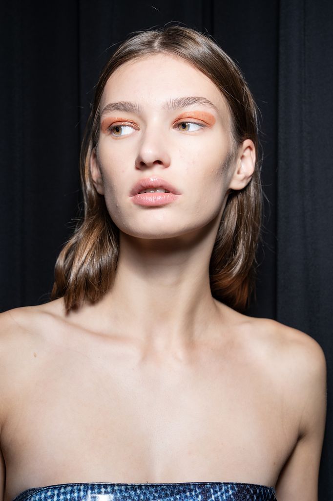 Modelo con sombra de ojos naranja, vestido palabra de honor y pelo suelto a la altura de la clavícula
