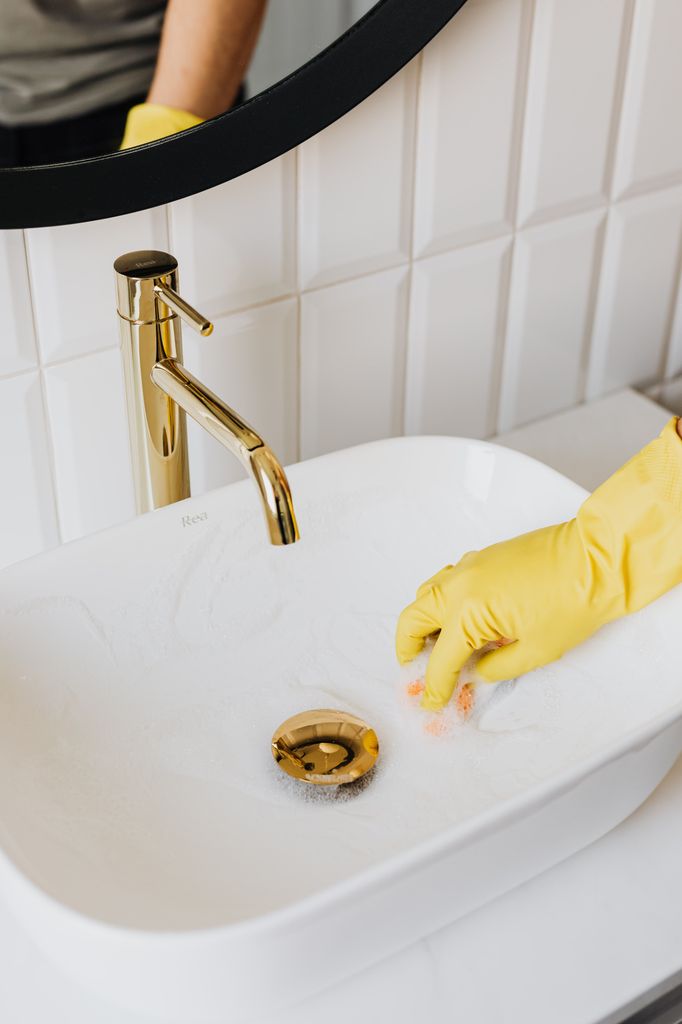 Persona limpiando un lavabo.