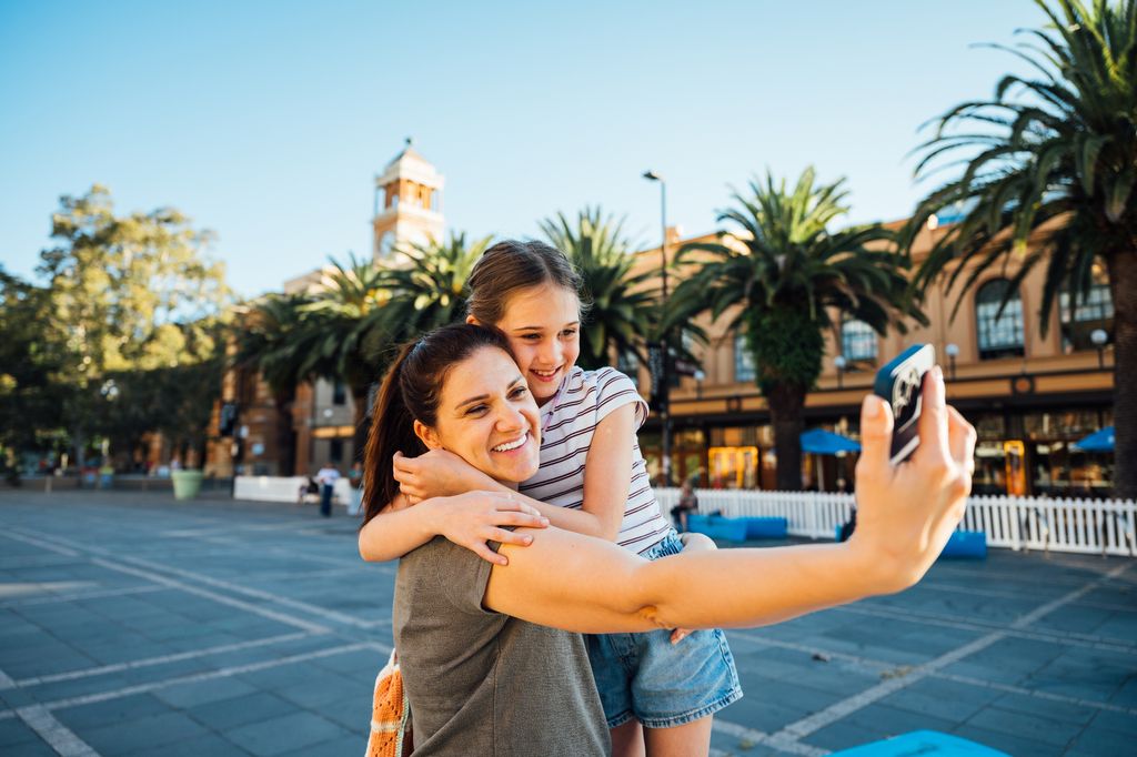 mujer y niña abrazadas en la calle, haciéndose un selfie