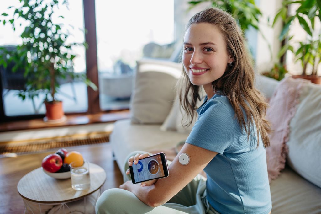 mujer con un dispositivo en el brazo para medir sus niveles de glucosa con el móvil