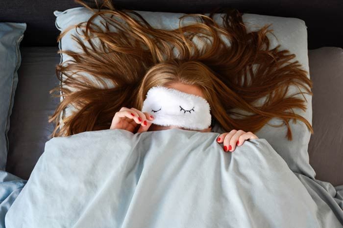 mujer en la cama con antifaz