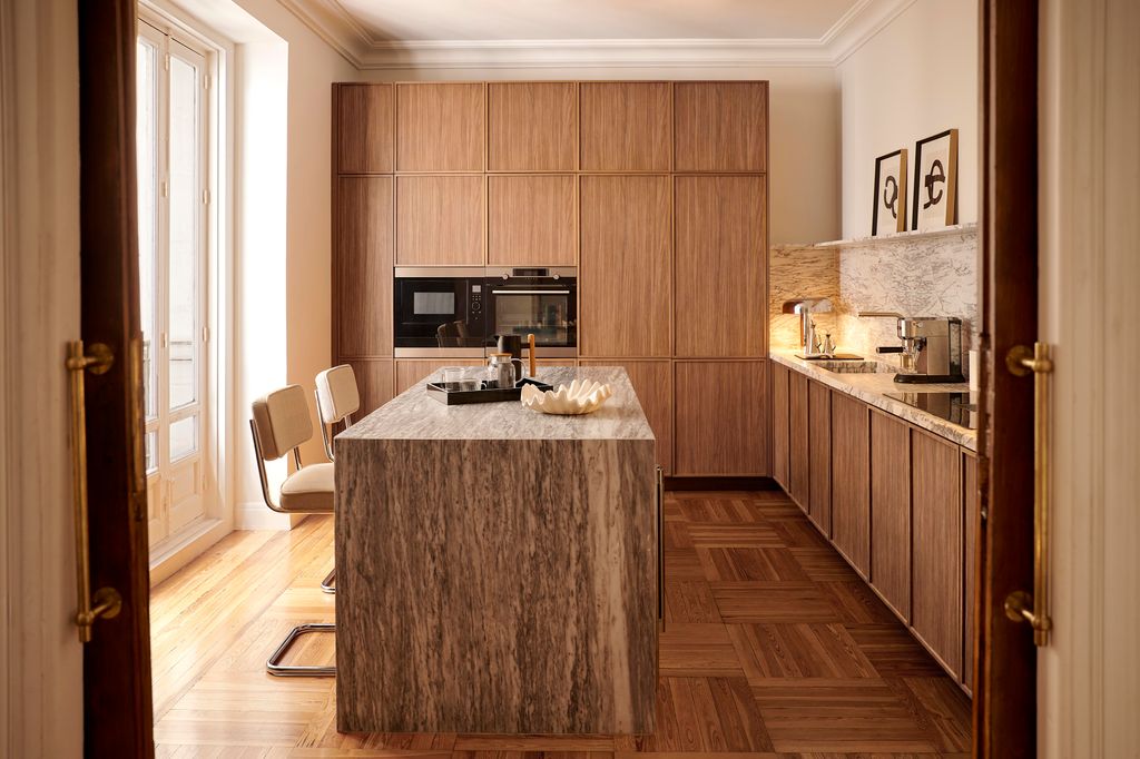 El mobiliario de madera y la encimera de granito natural aportan calidez a esta cocina de líneas contemporáneas que mantiene los electrodomésticos integrados