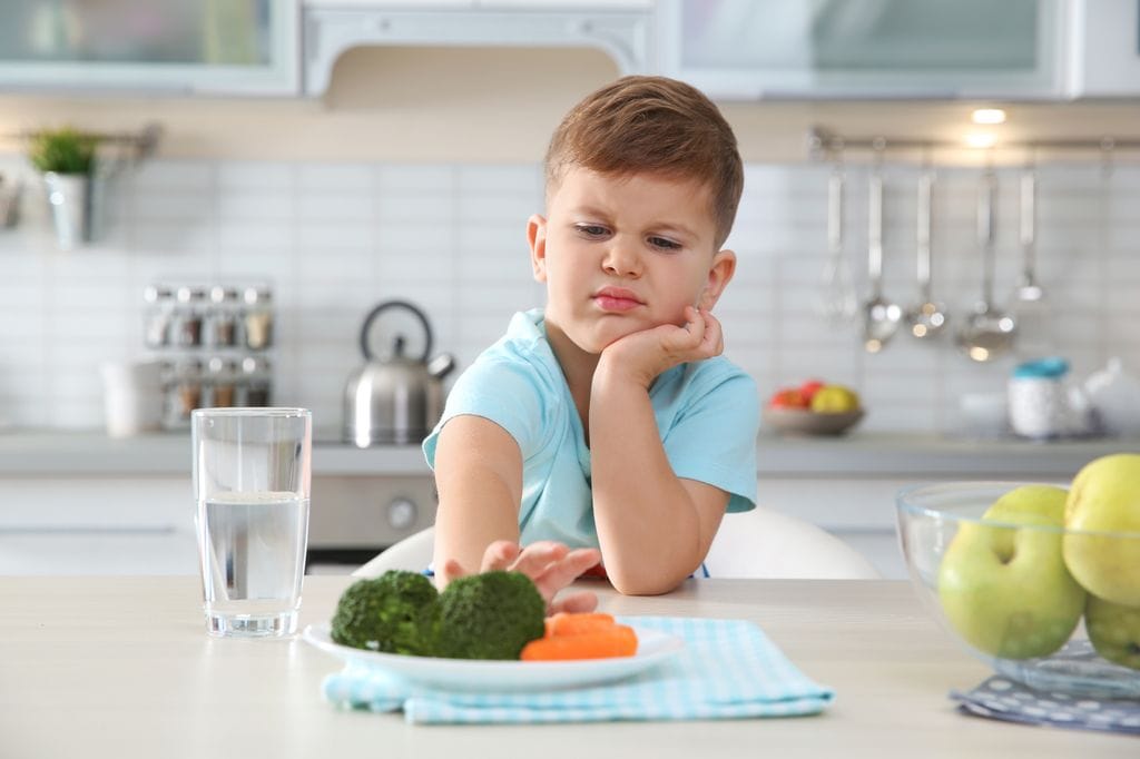 Niño pequeño rechazando un plato de verdura
