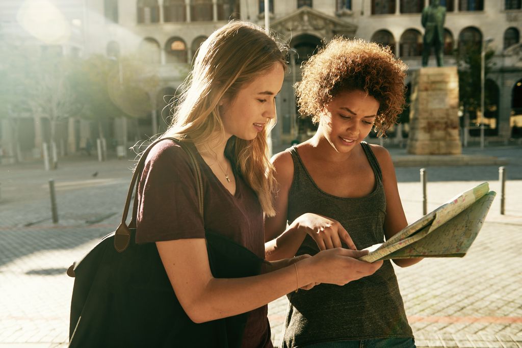 dos amigas mirando un mapa mientras hacen turismo