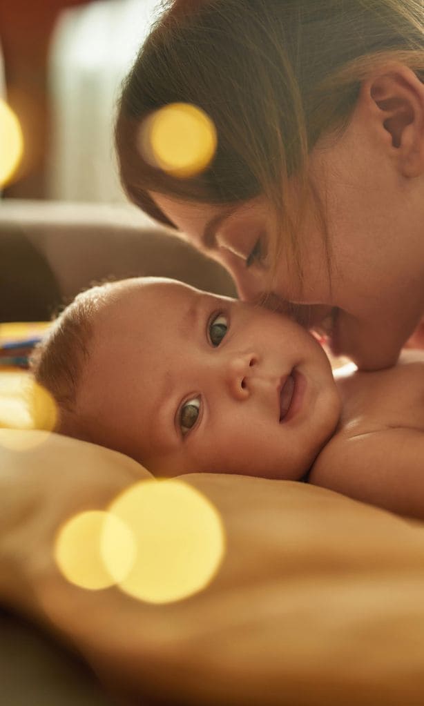 Bebé con mamá besándole