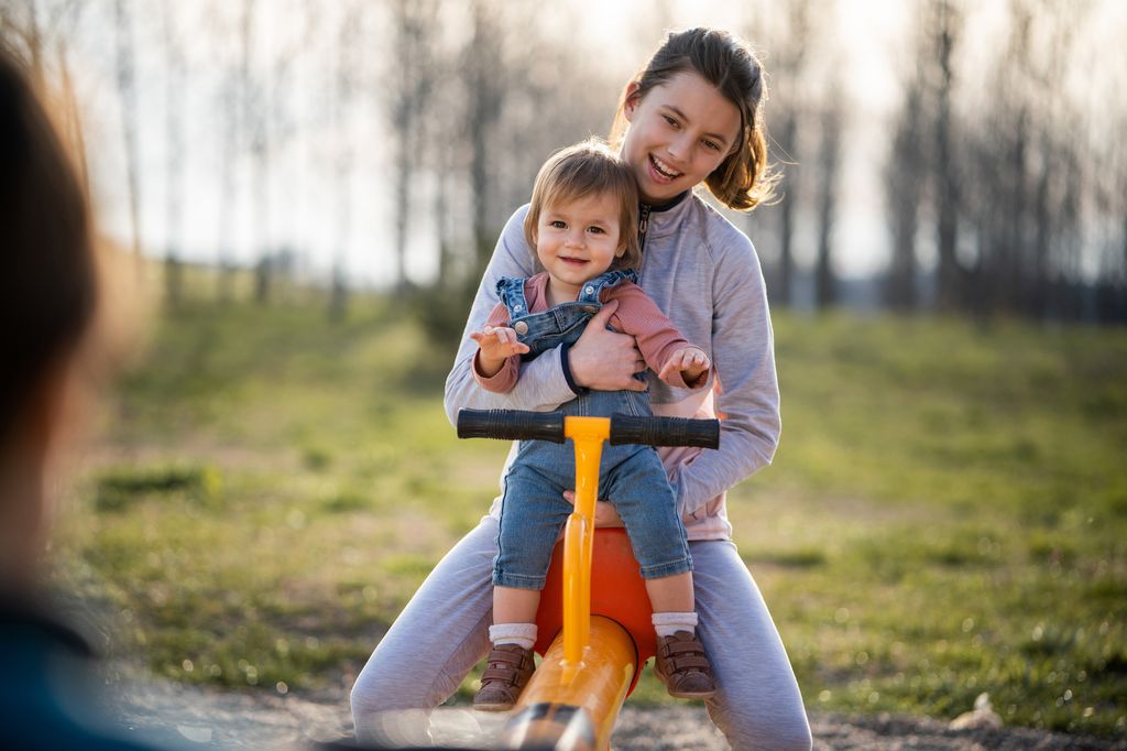 hermana mayor con su hermana pequeña jugando en el parque