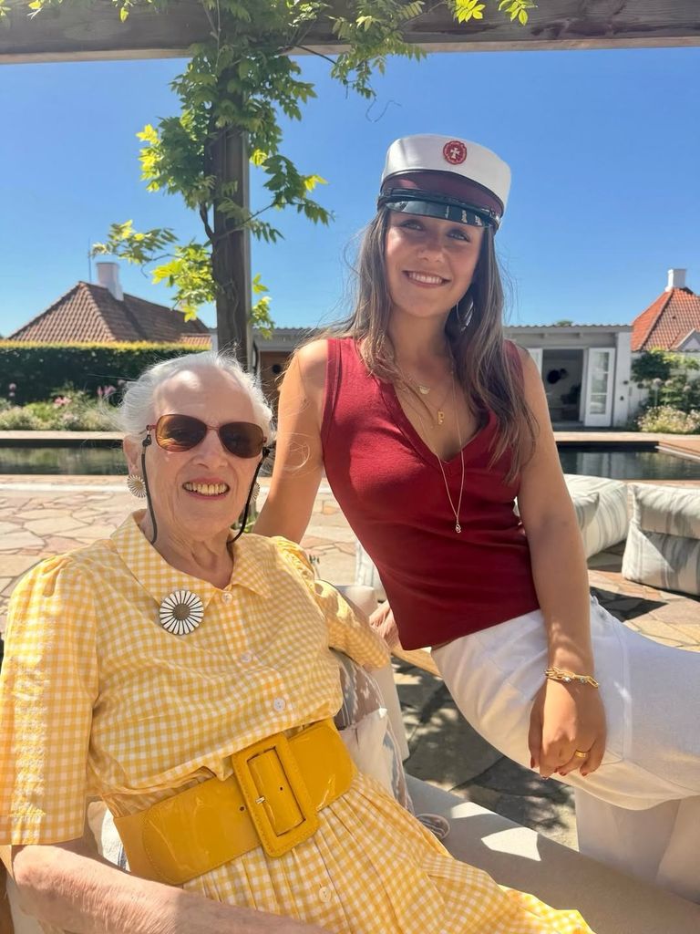 Dos mujeres sonrientes, una con vestido amarillo y otra con uniforme de marinera, posan juntas.