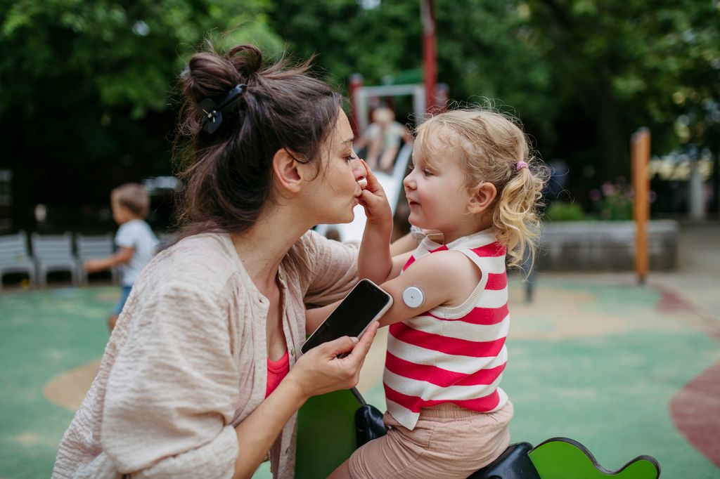 madre con su hija diabética, que tiene un sensor de glucosa en el brazo