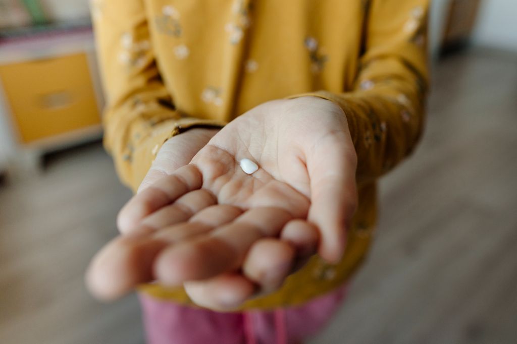 Niña con una pastilla en la mano para tomársela